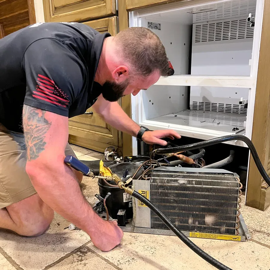 Technician servicing a refrigerator sealed system